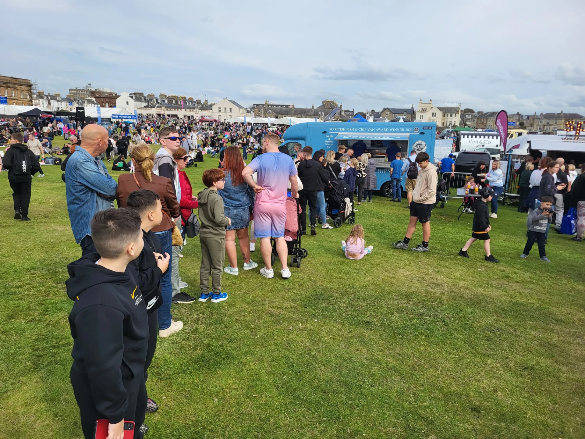 A large festival crowd queuing at Joanna's Chippy Van