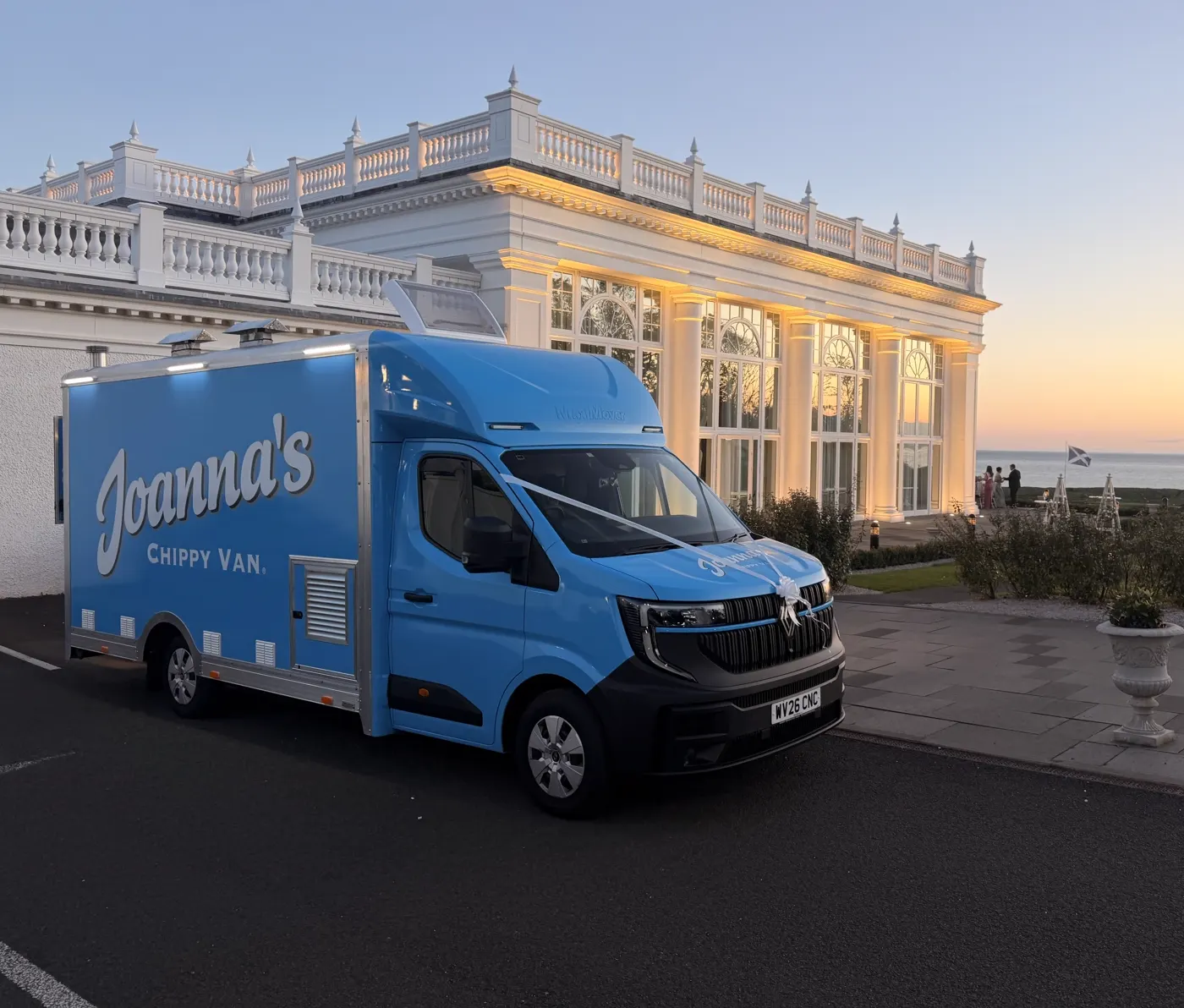 Joanna's Chippy Van decorated with wedding ribbon outside a Scottish coastal wedding venue at sunset
