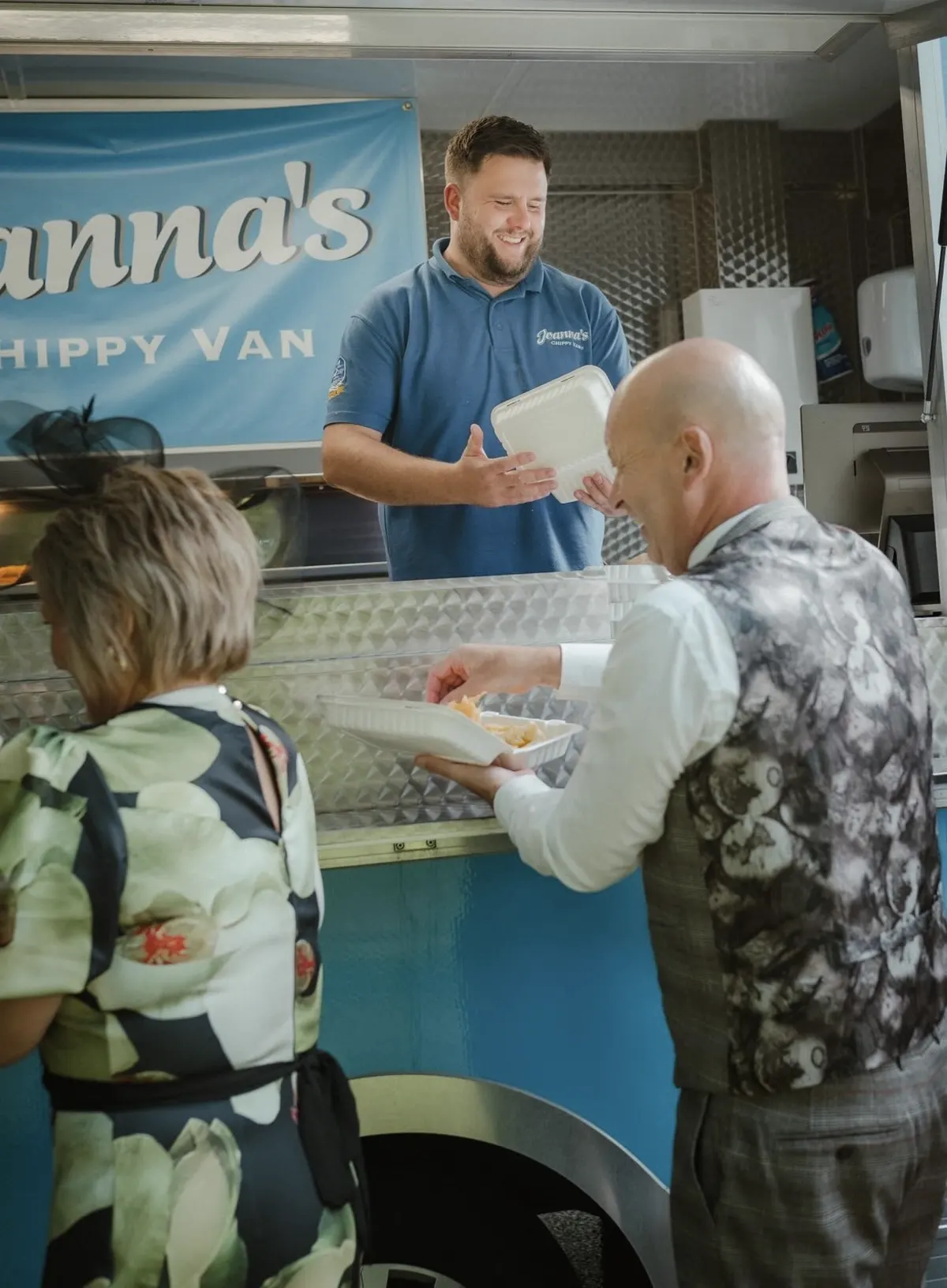 A member of the Joanna's Chippy Van team serving fish and chips to wedding guests